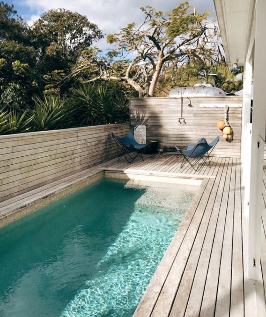 Timber deck boards surrounding a rectangular swimming pool with horizontal slat privacy fencing
