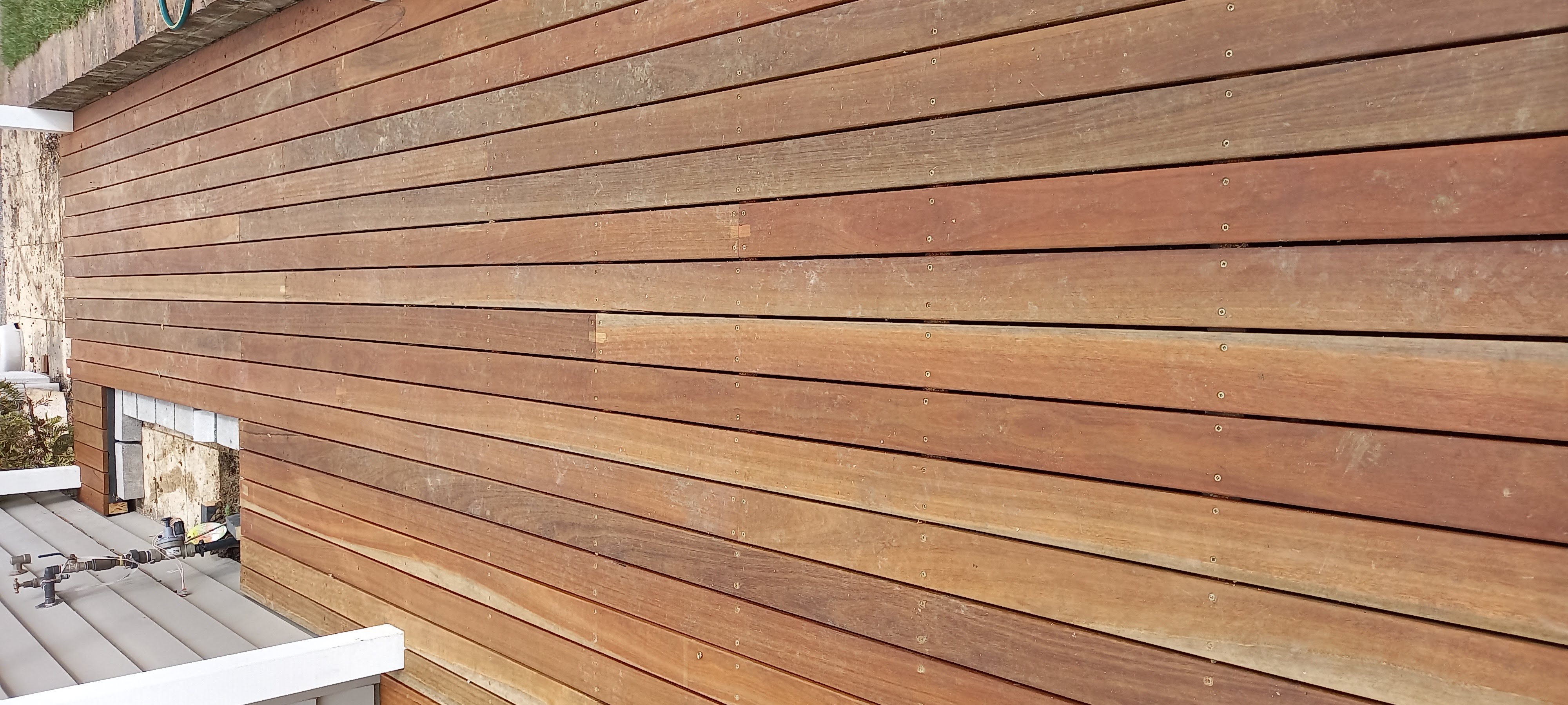 Spotted gum hardwood decking boards with visible grain and screw fixings
