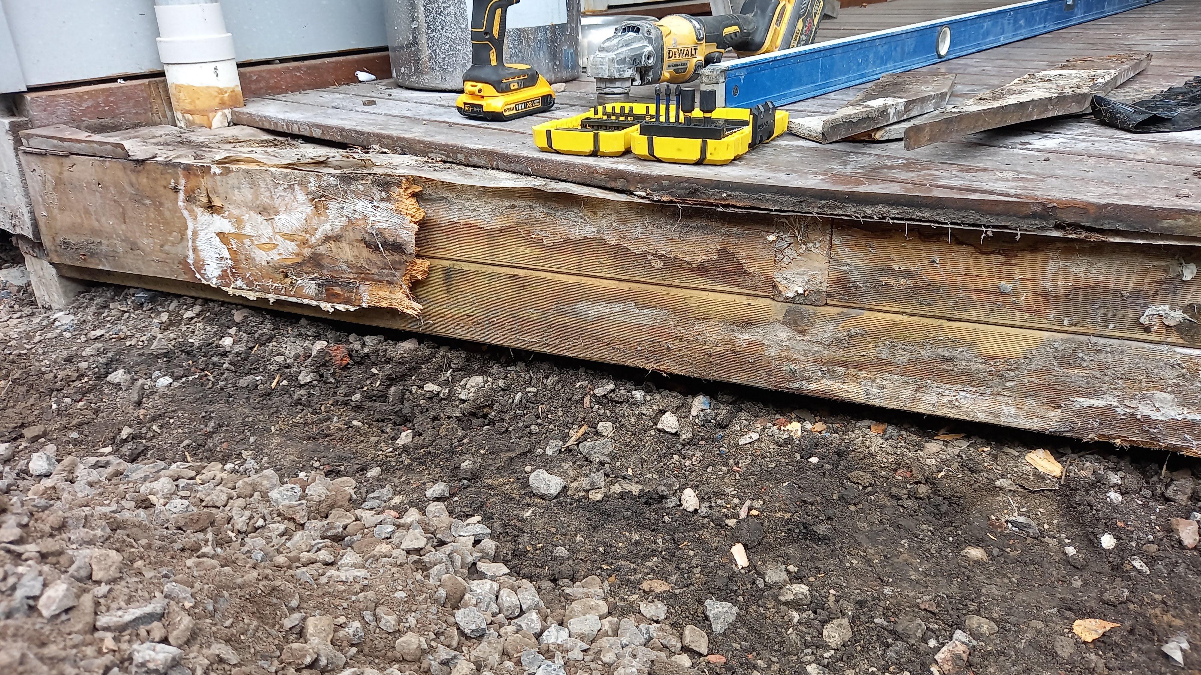 Rotting deck rim joist with peeling timber caused by poor ventilation and trapped moisture